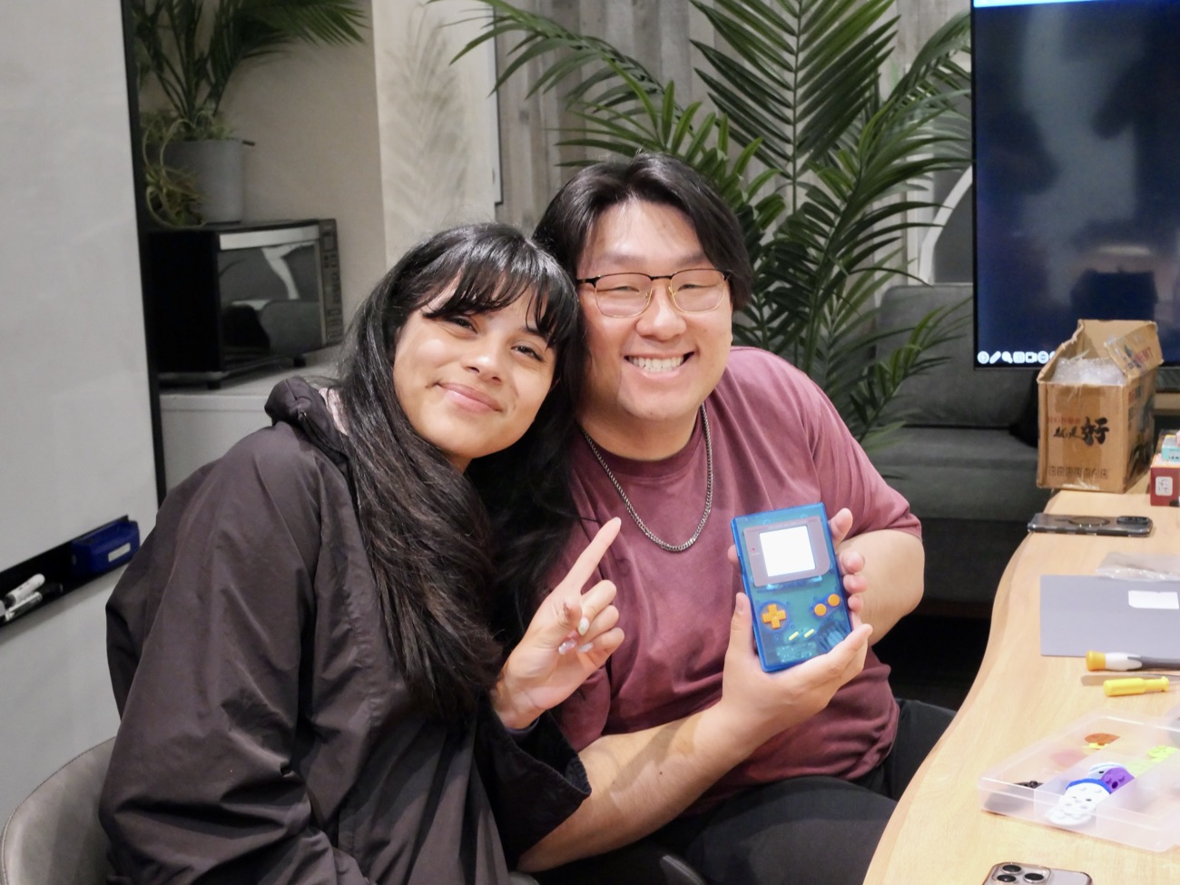 A couple posing happily with their blue custom Game Boy