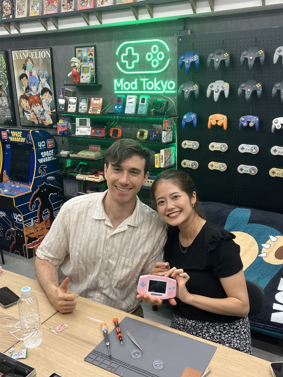 A couple giving a thumbs-up with their finished pink Game Boy Advance
