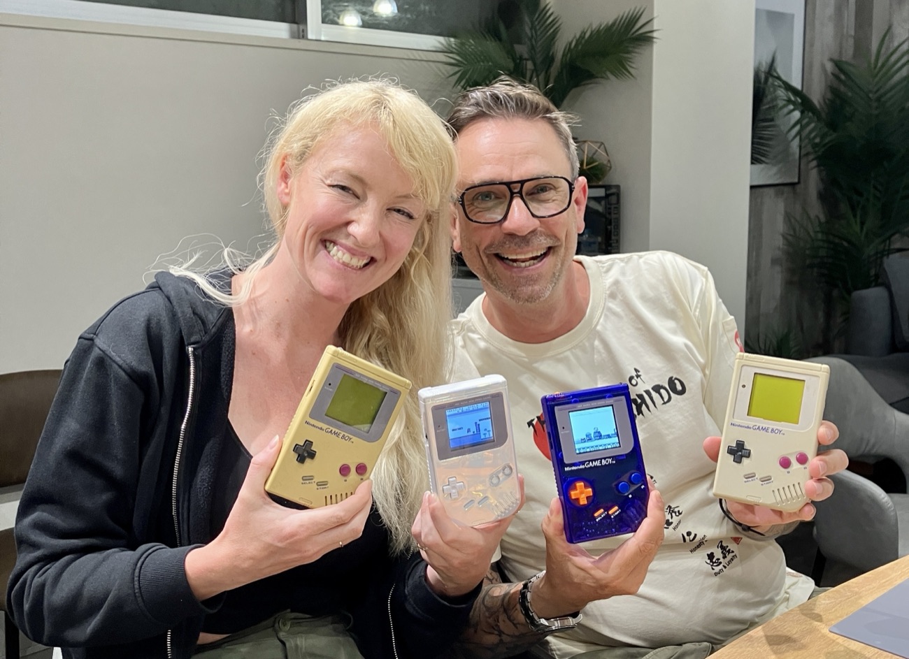 Two guests beaming, holding four finished Game Boys